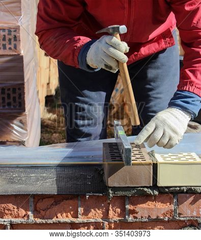 Bricklayers Hands With In Masonry Trowel Bricklaying New House Wall On Foundation. Close Up Of Indus