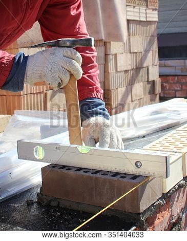 Bricklayers Hands With In Masonry Trowel Bricklaying New House Wall On Foundation. Close Up Of Indus