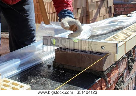 Bricklayers Hands With In Masonry Trowel Bricklaying New House Wall On Foundation. Close Up Of Indus