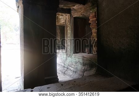 Sun Shining Through A Window At Stone Pillar With Ancient Murals In Famous Histroical Angkor Wat Rui