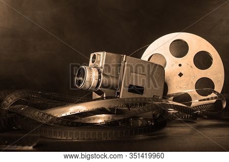 8 Mm Movie Camera With A Reel Of Film In Smoke. Dark Background. Black And White