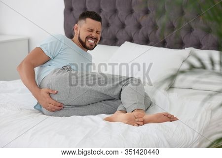 Man Suffering From Hemorrhoid On Bed At Home