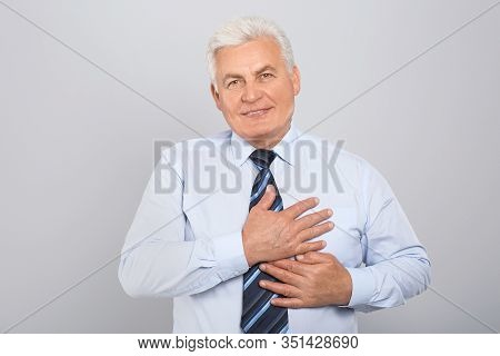 Grateful Senior Man With Hands On Chest Against Light Grey Background