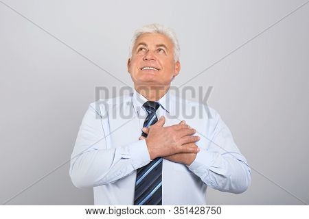 Grateful Senior Man With Hands On Chest Against Light Grey Background