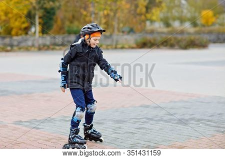 Cute School Kid Boy Skating With Rollers In The City. Happy Healthy Child In Protection Safety Cloth