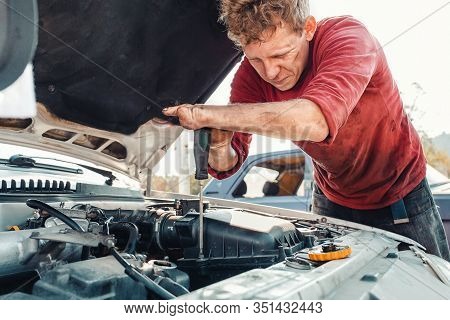 The Concept Of Disability Of People And Their Adaptation To Life. A Blond Disabled Man Repairs A Car