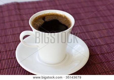 wunderschÃ¶ne weiÃŸe Tasse mit heiÃŸen schwarzen Kaffee auf hÃ¶lzernen Hintergrund