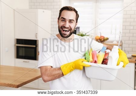 Image of young optimistic positive man househusband indoors.