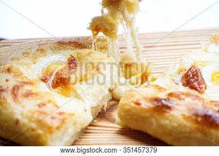 Adjarian Khachapuri With Quail Eggs And Cheese On A Wooden Board. Close-up. Georgian Cuisine. Nation