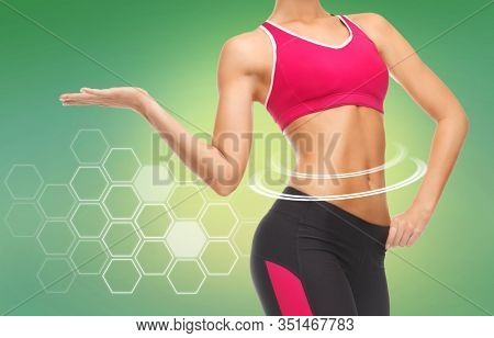 sport, fitness and diet concept - close up of slim fit woman's body with trained abs over green background