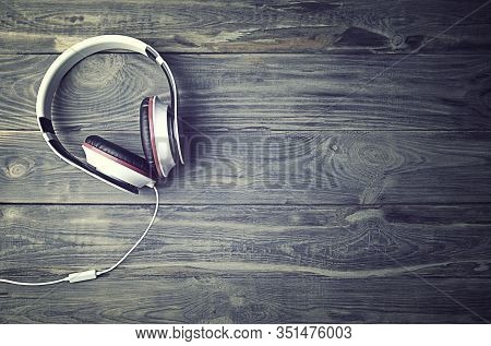 Minimalist  Photo Of Earphones With Copy Space. White Dj Headphones With Cable On Old Woodenl Backdr