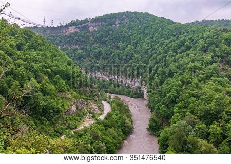 A Gorge In The Mountains With A Suspension Bridge Over It. Skybridge Suspension Bridge Over A Precip