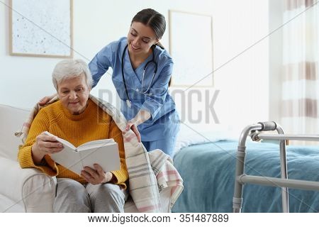 Care Worker Covering Elderly Woman With Plaid In Geriatric Hospice