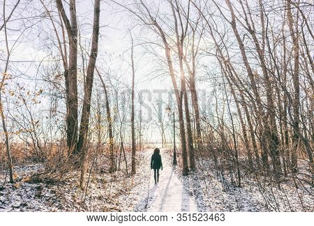 Winter city park outdoor walk woman walking in snow in snowy forest path in sunny day, active people. Outside leisure. girl hiking in nature.
