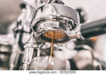 Coffee machine espresso extraction pouring from bottomless naked portafilter. Professional equipment at home or cafe shop. Closeup of brown crema.