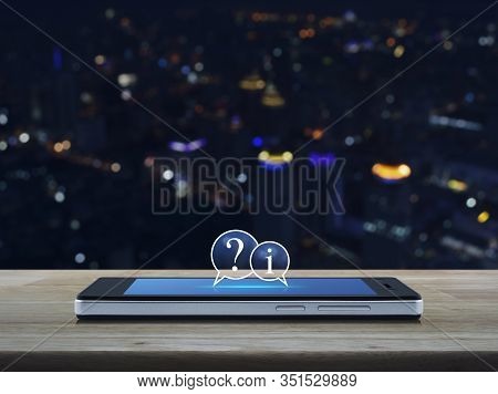 Question Mark And Information Chat Icon On Modern Smart Mobile Phone Screen On Wooden Table Over Blu