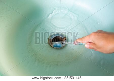 Woman's Right Hand Holding Toothbrush For Cleaning Green Washbasin, Bathrooom Cleaning Concept