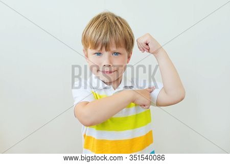 Portrait Of A Strong Kid Showing The Muscles Of His Arms On White Background