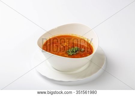 Beef Goulash Soup With Tongue. A White Oval Plate With Red Soup Stands On A White Background.