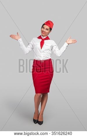 Full Length Air Hostess Smiling And Pointing At Left And Right Exits During Pre Flight Safety Demons