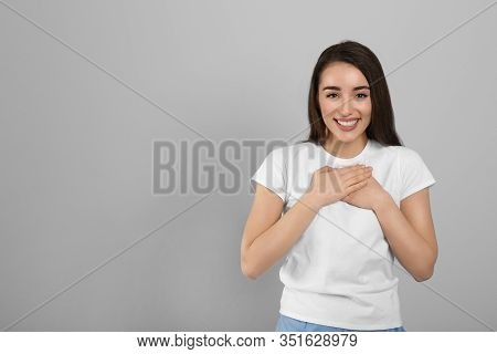 Beautiful Grateful Woman With Hands On Chest Against Light Grey Background. Space For Text