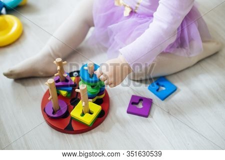 Girl Plays Toys In Living Room. Montessori Wooden Toy Folded Pyramid. Circle, Quadra, Triangle, Rect