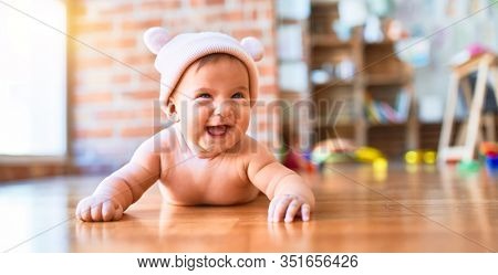Adorable baby lying down on the sofa smiling happy at home. Newborn with smile on face wearing fanny hat relaxing and resting comfortable