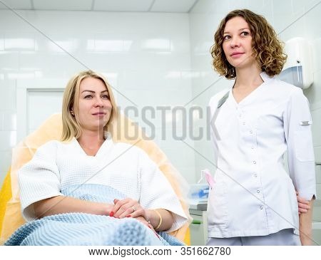 Woman Wearing Disposable Medical Bathrobe Being At Consultation In Cosmetology Clinic. Attractive Fe