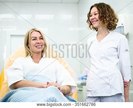 Woman Wearing Disposable Medical Bathrobe Being At Consultation In Cosmetology Clinic. Attractive Fe