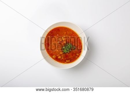 Beef Goulash Soup With Tongue. A White Oval Plate With Red Soup Stands On A White Background. The Vi