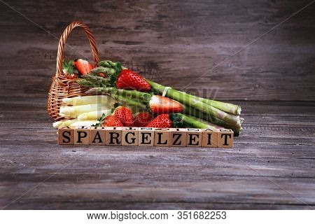 White And Green Asparagus With Strawberries On Rustic Background With Spargelzeit Wooden Letter.