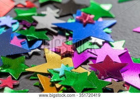 Party Confetti Multi Colored Stars And Shaped Close Up Scatted On A Black Table