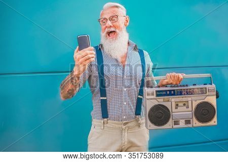 Senior Hipster Man Using Smartphone App For Creating Playlist Music - Trendy Tattoo Guy Having Fun W