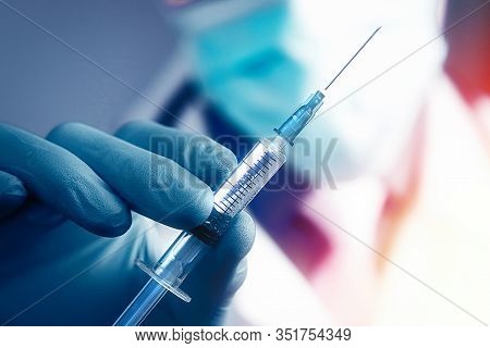 Close Up Hand Of Doctor In Blue Latex Glove And Medical Gauze Mask With Transparent Syringe. Health 