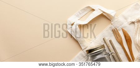 Cotton bag, bamboo cultery, glass jar, bamboo toothbrushes, hairbrush and straws on color background, flat lay.