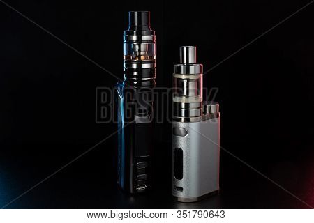 Electronic Cigarettes Or Vaping Devices On Black Background. Toned Light