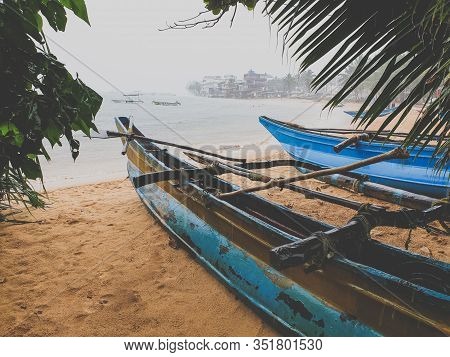 Toned Image Of Heavy Tropical Rain On The Beach. Old Wooden Fishing Boats On The Sandy Ocean Beach.