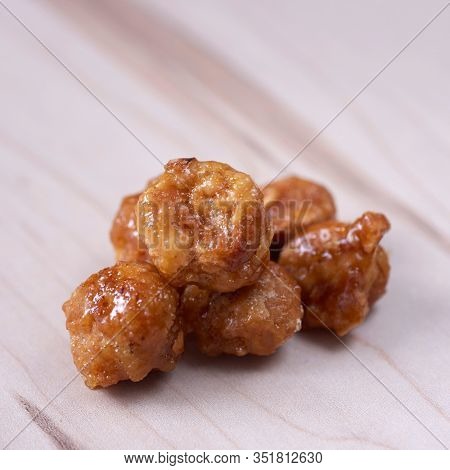 closeup of some nueces de macadamia garrapinadas, spanish candied macadamia nuts, on a wooden table