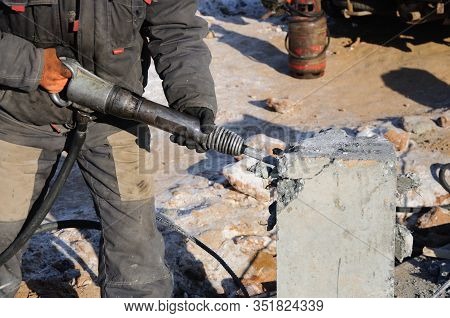 Demolition Of Rebots At The Construction Site. Builder With Hammer Breaking Pills. Demolition With A