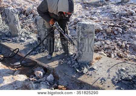The Process Of Dismantling Works With A Jackhammer. A Worker Beats The Concrete From The Column.