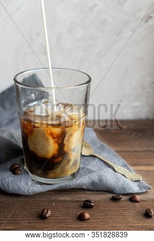A Stream Of Milk Pours Into Coffee