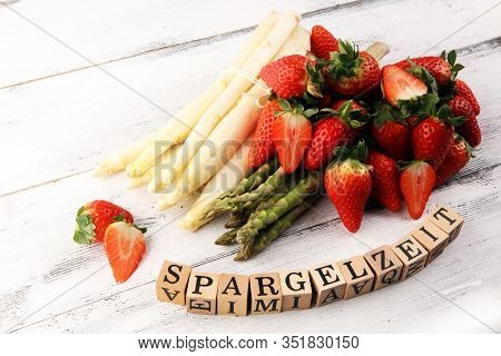 White And Green Asparagus With Strawberries On Rustic Background With Spargelzeit Wooden Letter.