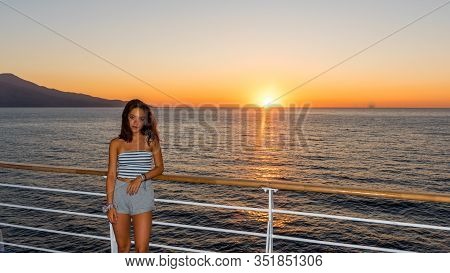 Asian Teen In Tube Top Standing On Deck Of Ferry Looking Away From Sunset On Ferry To Greece