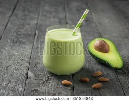 A Glass Of Smoothies And A Cocktail Tube And Avocado On A Wooden Table. Fitness Product. Dietary Spo