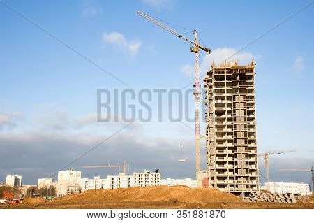Tower Cranes Working At Construction Site Against Blue Sky. Crane Lifting A Concrete Bucket. Constru