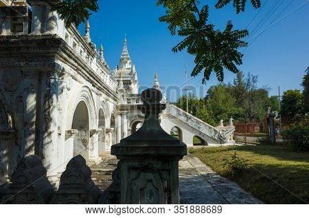 White wall with archs and garden of Atumashi Monastery, formally Maha Atulaveyan Kyaungdawgyi - Buddhist monastery in Mandalay, Myanmar