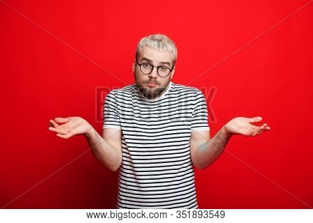 Handsome Caucasian Boy With Beard And Blonde Hair Is Looking Through Eyeglasses And Showing His Inde