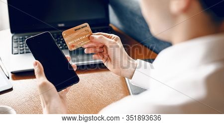 The Upper View Of A Caucasian Businessman Using A Bank Card And His Mobile To Buy Something