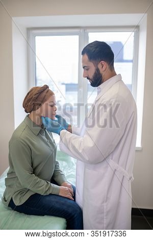 Tall Doctor In Blue Gloves Palping Lymph Nodes Of Female Patient