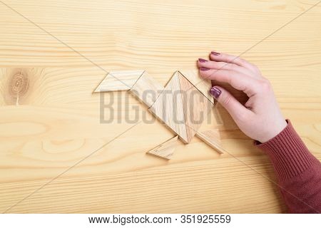 Girl Collects A Wooden Tangram Puzzle On A Wooden Table. Chinese Tangram Puzzle. Puzzle Concept.